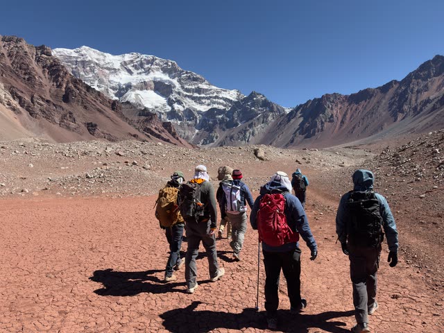 Group of hikers walking toward towering mountain wall