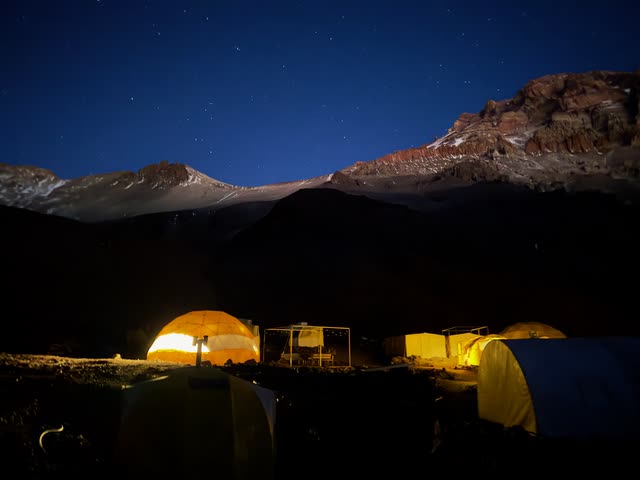 Long-exposure night photo of camp under starry sky
