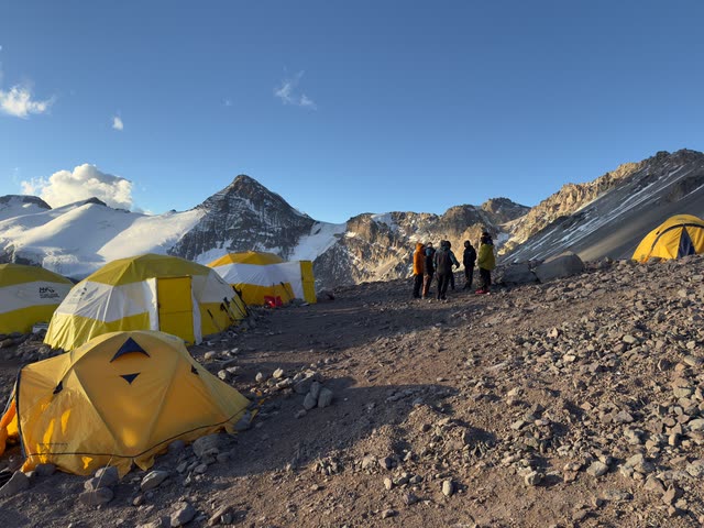High-altitude camp with tents and hikers in winter gear