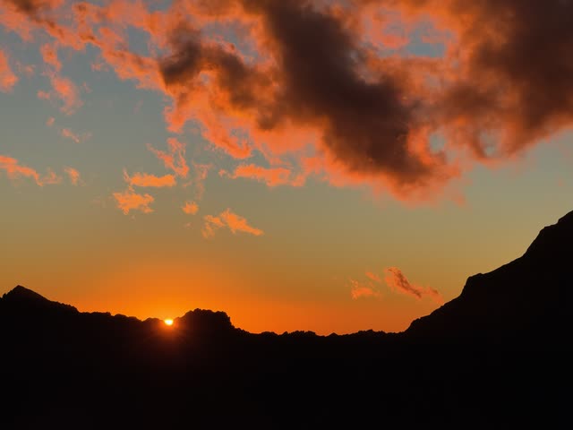 Sun dipping behind mountain ridge