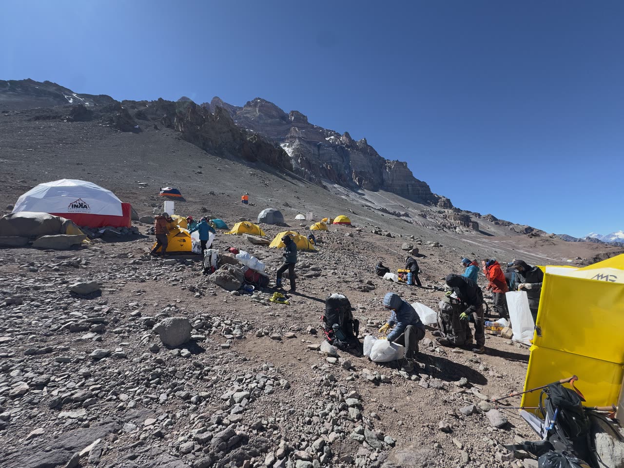 High-altitude camp with tents and flag on barren terrain
