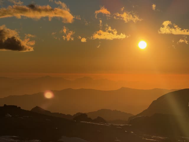 Hazy golden sun over jagged peaks