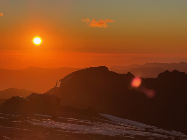 Sun flare over dark mountain crest