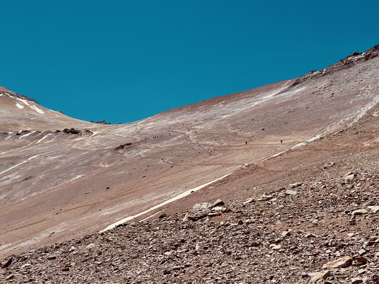 Steep barren gravel slope under clear blue sky