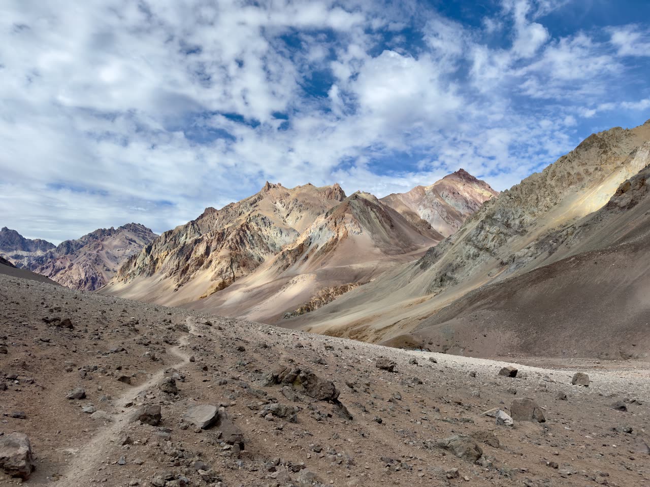 Winding path through rocky valley with snow in distance