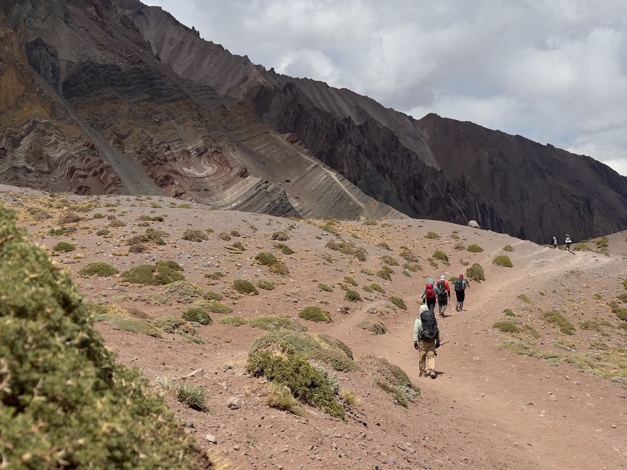 Group of hikers descending a dusty trail in wide valley