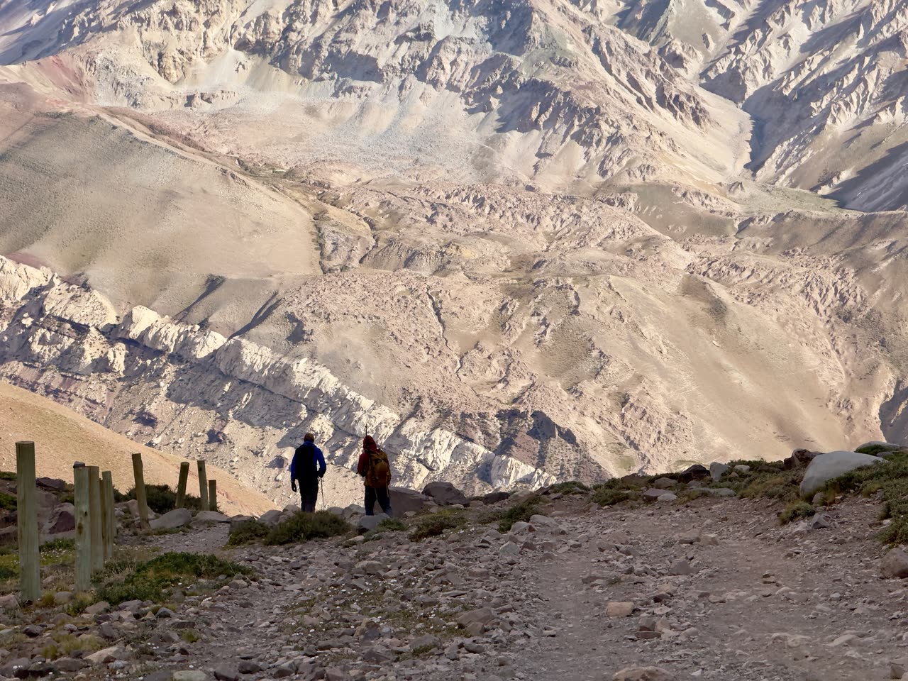 Two people walking on broad gravel path through wide valley
