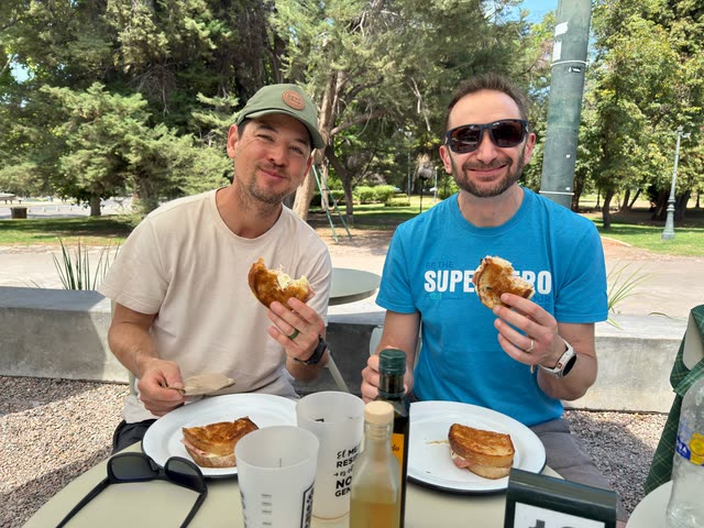 Two men at outdoor table enjoying pastries